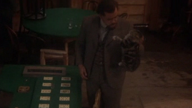 McCabe and Mrs. Miller - Smalley John Schuck holding long-haired tabby cat roughly by scruff