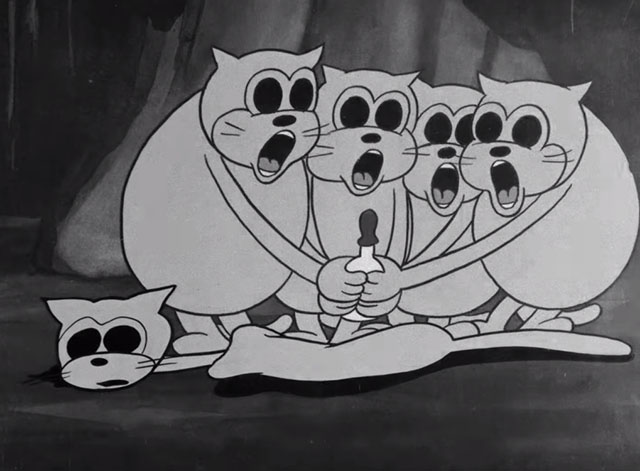 Minnie the Moocher - depleted ghost cat lying on her side with four fat kittens holding bottle