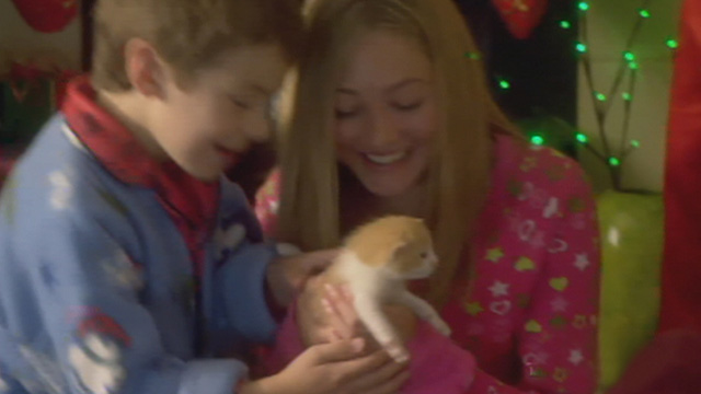 Mistletoe Over Manhattan - Bailey Olivia Scriven and brother Travis Peter DaCunha smiling over tiny orange and white kitten