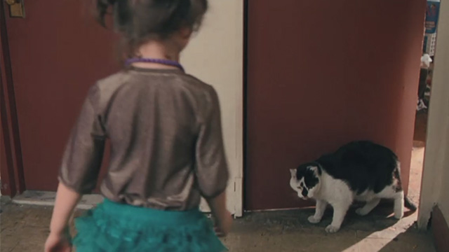 Motherhood - little girl Celina Vignaud approaching tuxedo cat Lady in corridor