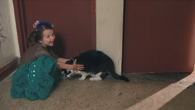Motherhood - little girl Celina Vignaud petting tuxedo cat Lady in corridor