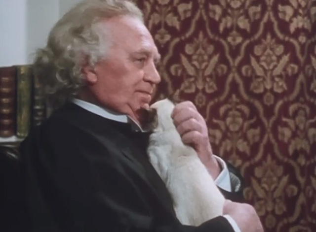 A Murder of Quality - Head Master Terence Fielding sitting down with Siamese cat