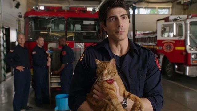 The Nine Lives of Christmas - orange tabby cat Ambrose Trace held by Zachary Brandon Routh in firehouse