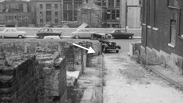 Passport to Shame - Room 43 - black and white cat sitting by wall on demolished street