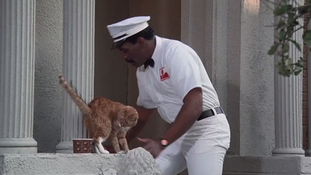 Police Academy 6: City Under Siege - Hightower Bubba Smith dressed as milkman with orange tabby cat on steps