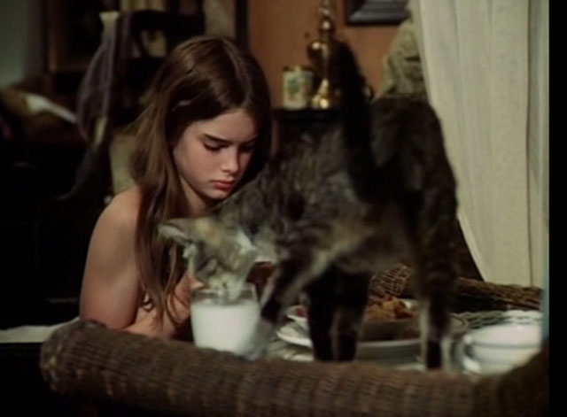 Pretty Baby - tabby cat drinking milk from glass in front of a young Brooke Shields