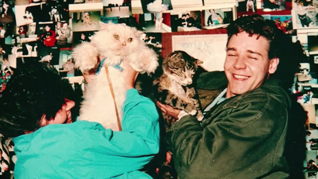 Proof - photo of limp Bengal tabby cat Ugly being held up by Andy Russell Crowe with woman holding cream colored Persian cat