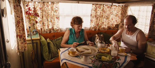 Red Dog - Mr. and Mrs. Cribbage Paul Blackwell and Jacquy Phillips sitting at kitchen table with longhair brown and white tabby cat Red Cat