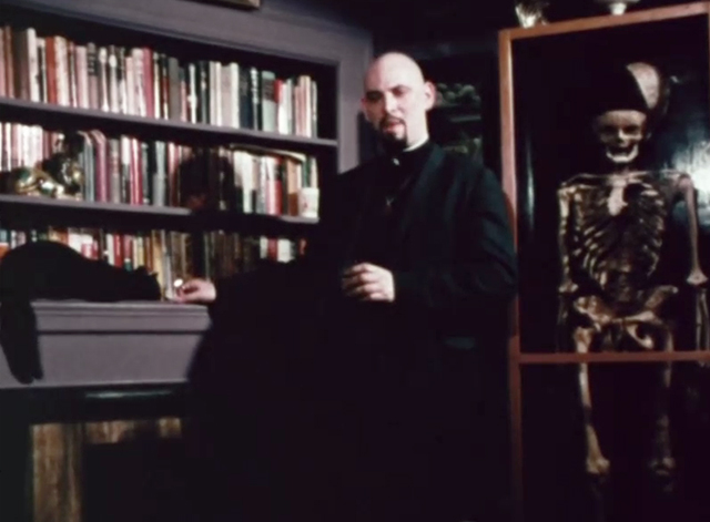 Satanis - Anton Szandor LaVey standing next to bookcase and black cat