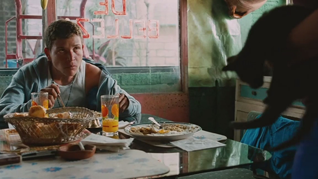 Sin Nombre - Willy Edgar Flores looking up at Aunt holding gray cat at table