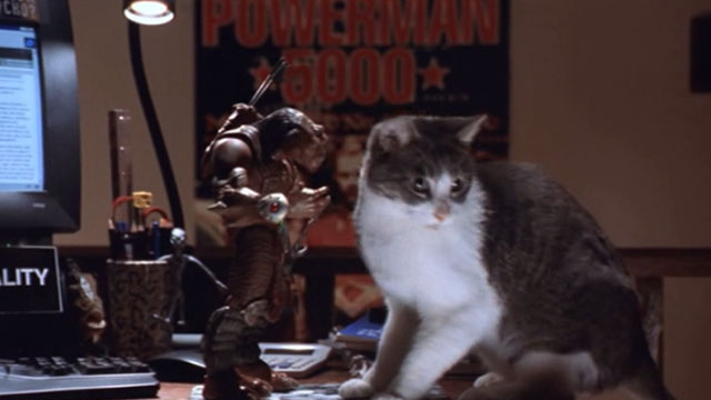 Small Soldiers - gray and white tabby cat beside Archer toy Gorgonite on desk