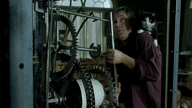 Histoire de Marie et Julien - The Story of Marie and Julien - Jerzy Radziwilowicz with tuxedo cat Nevermore Gaspard on shoulder while working on clock