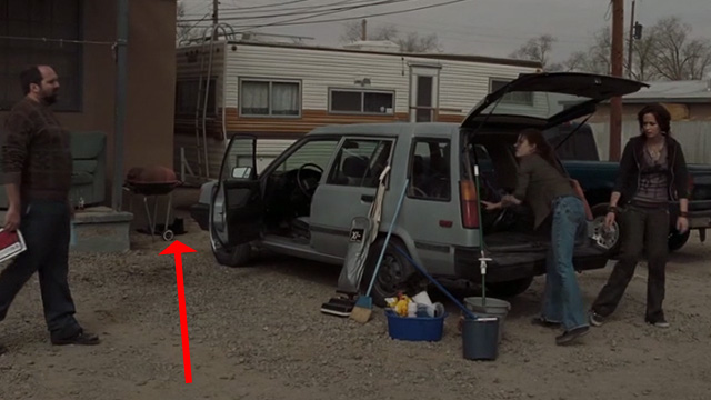 Sunshine Cleaning - black cat sitting beneath barbecue outside hotel