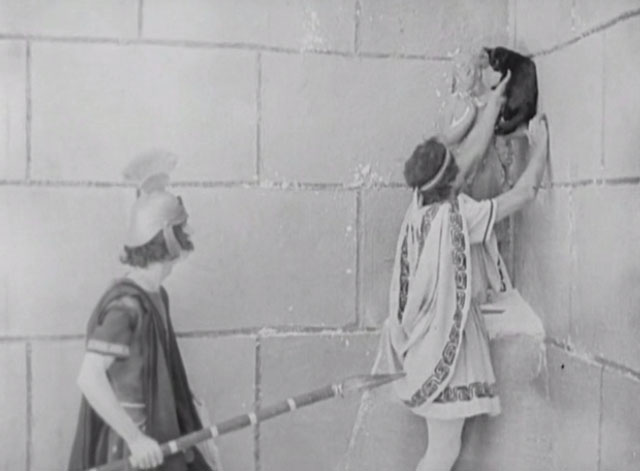 Three Ages - Buster Keaton taking down black cat from statue