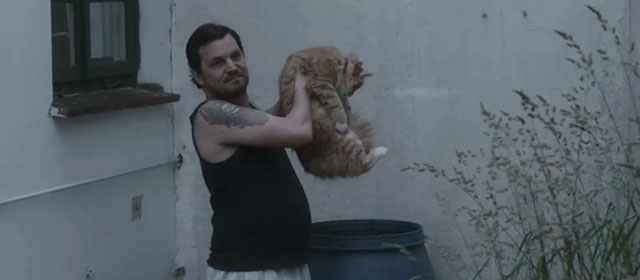 Tore tanzt - Nothing Bad Can Happen - Benno Sascha Alexander Gersak holding longhair ginger tabby cat over rain barrel