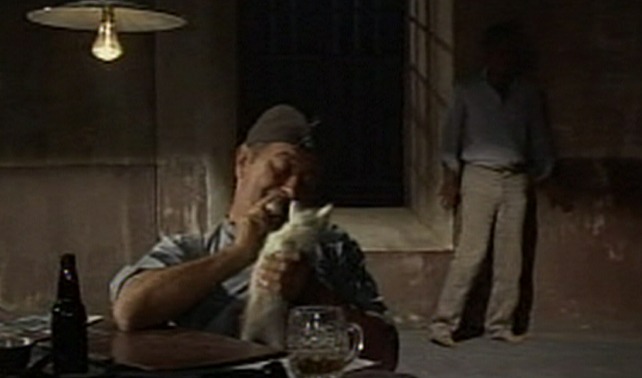 Triple Cross - guard holds up kitten while Eddie Chapman tries to sneak by