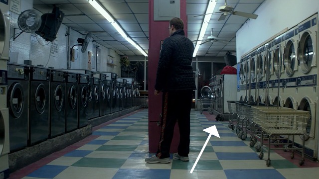 A Walk Among the Tombstones - black cat washing self in laundromat