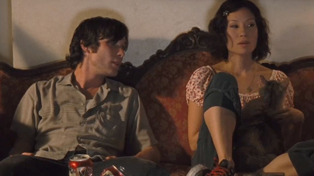 Watching the Detectives - Neil Cillian Murphy and Violet Lucy Liu sitting on couch petting longhair pastel calico cat