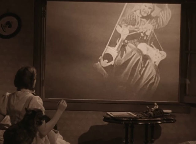 The Wizard of Oz - Dorothy Judy Garland looking at old woman knitting in rocking chair with cat in lap outside window in tornado