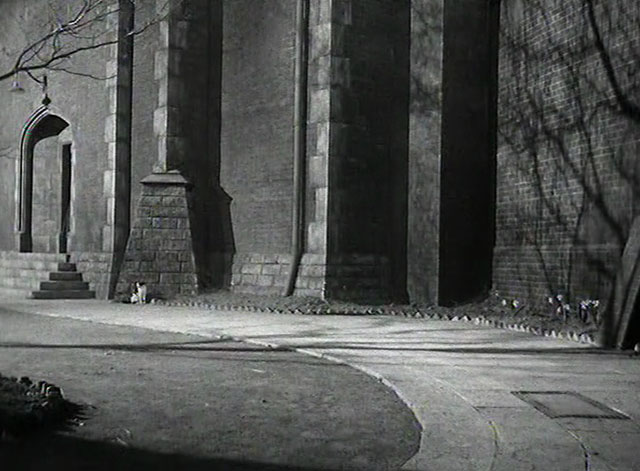 Yield to the Night - tuxedo cat sitting outside prison walls