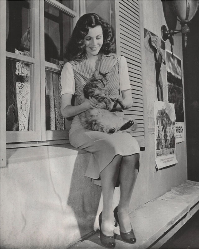Frances Dee on set of Flotsam So Ends Our Night with longhair tabby cat