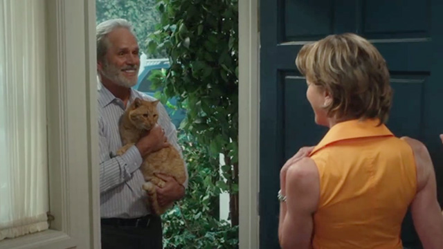 American Housewife - Grandma's Way - Dan Gregory Harrison in doorway holding ginger tabby cat Mittens
