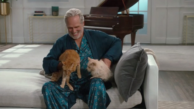 American Housewife - Highs and Lows - Dan Gregory Harrison sitting with ginger tabby cat Mittens and long haired cream cat
