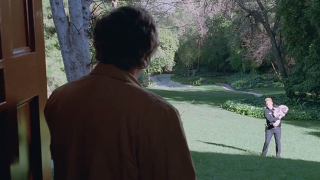 Columbo - A Trace of Murder - Peter Falk looking at Officer Will Nye holding silver Persian tabby cat on lawn