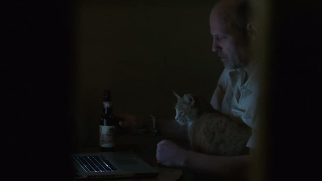 Elementary - Dead Man's Switch - ginger tabby cat on lap of Milverton David Mogentale looking at laptop computer