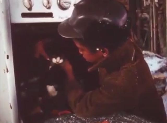J.T. - J.T. Kevin Hooks wrapping scarf around tuxedo cat in stove
