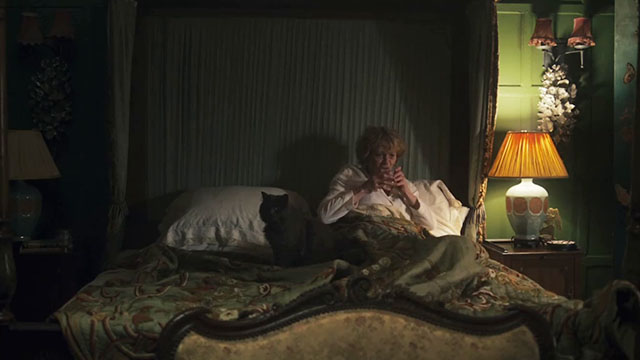 The Marlow Murder Club - Season One - Judith Samantha Bond sitting up in bed with gray longhair cat Jasper Thor