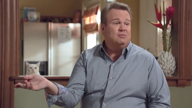 Modern Family - Larry's Wife - white cat Larry Frosty climbing onto counter behind Cameron Eric Stonestreet