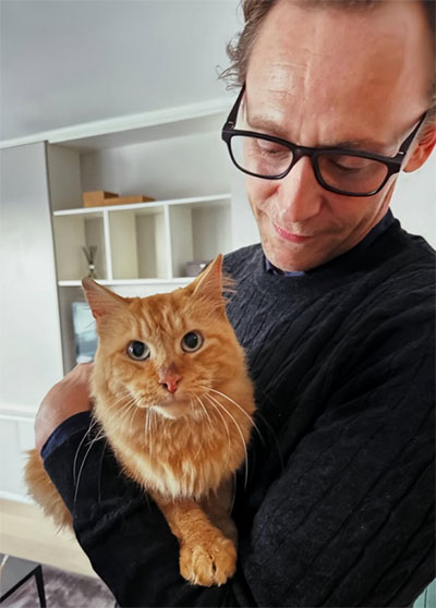 The Night Manager - Season 2, Episode 1 - Behind the scenes picture of Tom Hiddleston holding longhair ginger tabby cat Corky