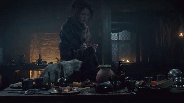 Outlander - The Wedding - dirty orange and white cat eating off leftover wedding scraps on table in front of Claire Caitriona Balfe