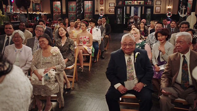 Superstore - Sandra's Wedding - older woman holding white cat Biscuit wearing captain's hat on lap during wedding ceremony