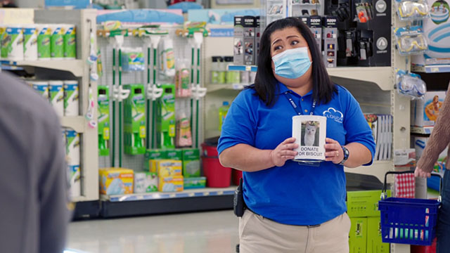 Superstore - Sandra's Wedding - Sandra Kaliko Kauahi holding donation tin for white cat Biscuit