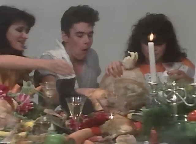 The One Thing - INXS - band members with women and a gray kitten feasting at table