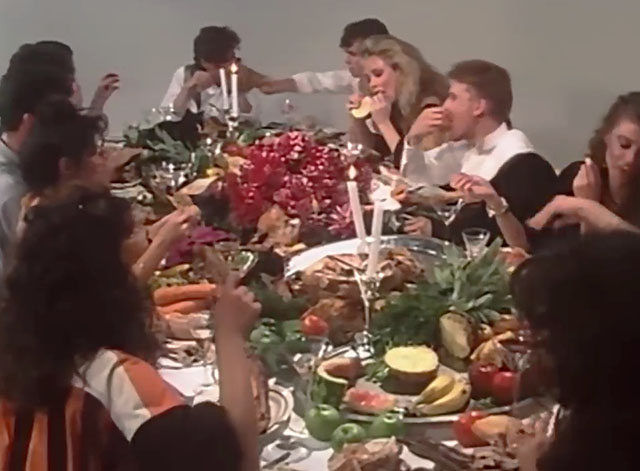 The One Thing - INXS - band members with women and a gray and white marbeled cat feasting at table